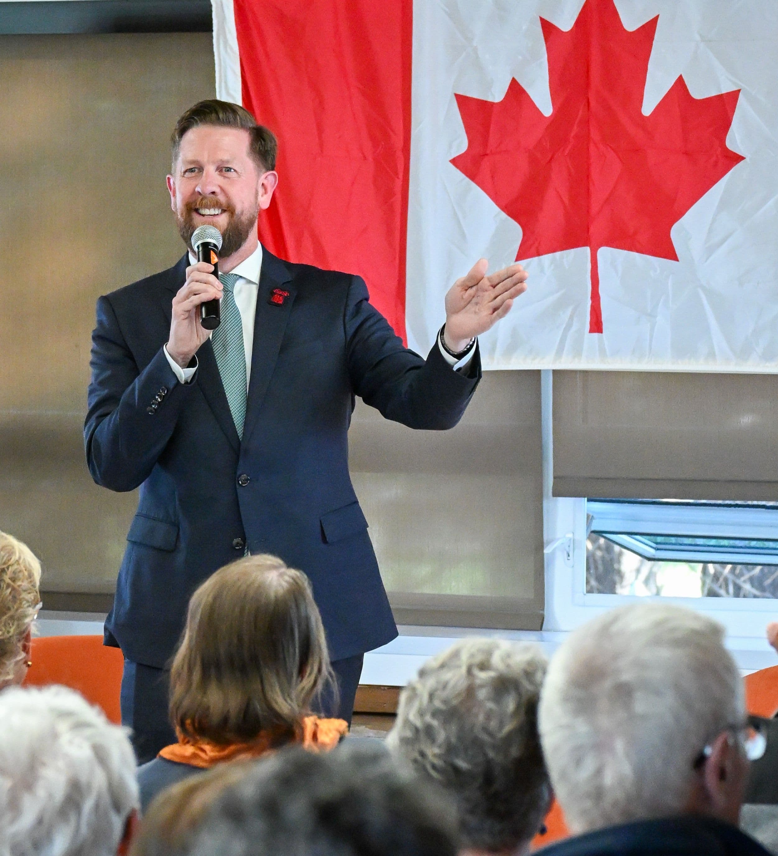 MLA Kyle Kasawski stands in front of a Canadian flag.